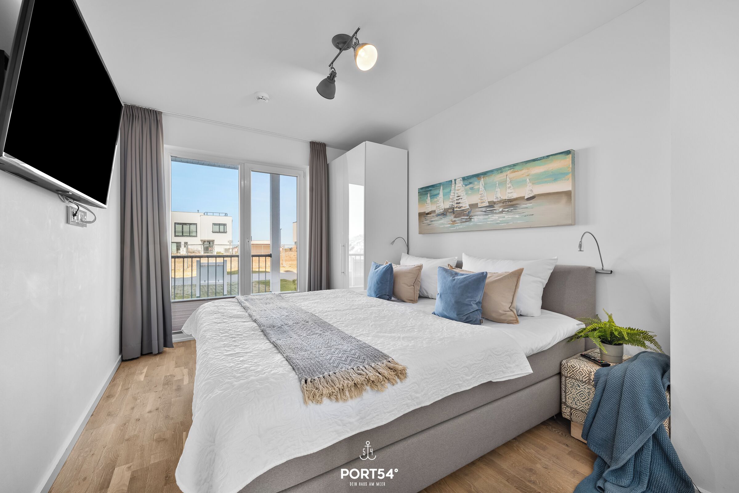 Ein modernes Schlafzimmer mit einem großen Bett, einem an der Wand montierten Fernseher und Blick auf die Stadt.