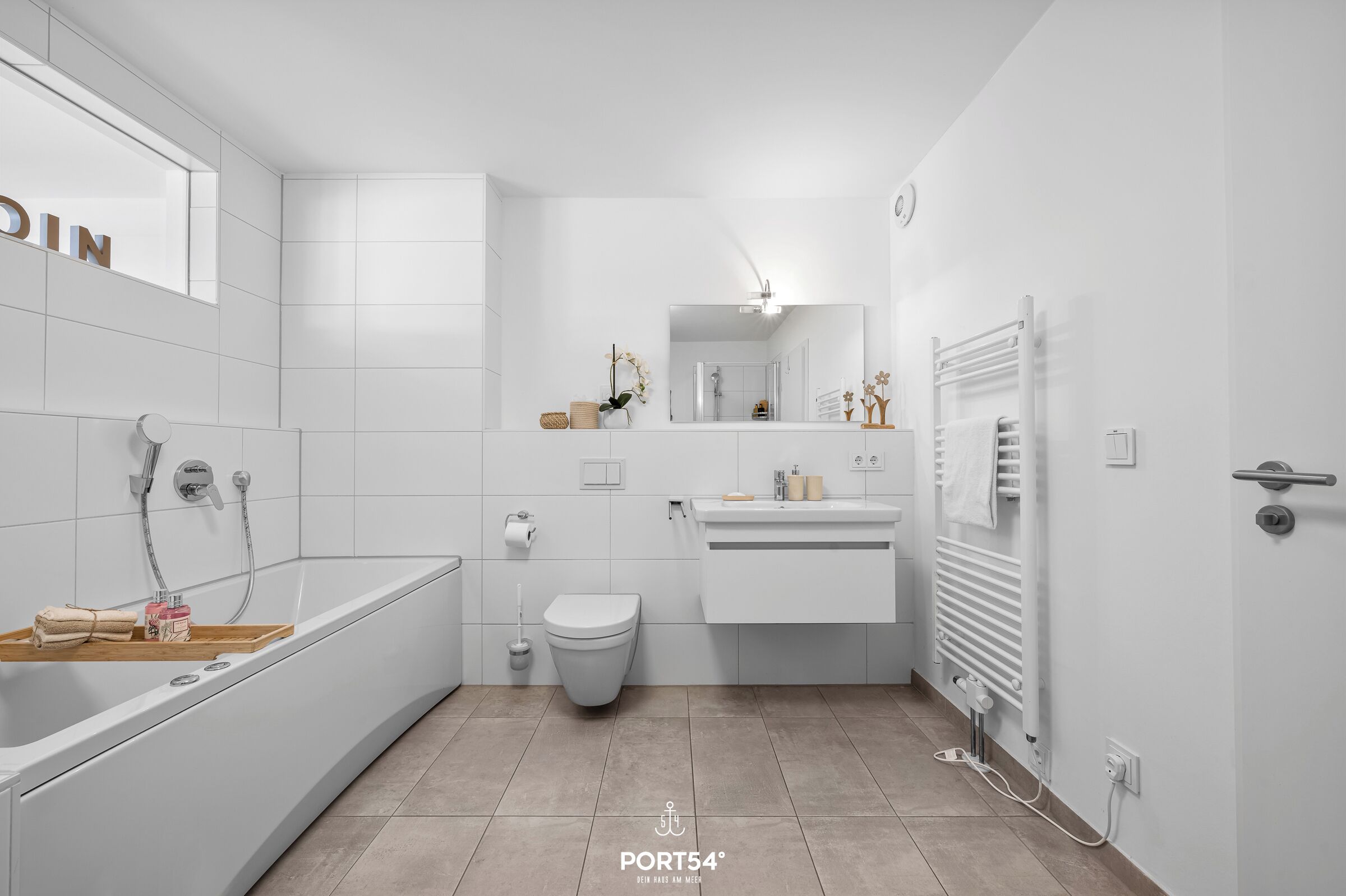 Et moderne badeværelse med badekar, toilet og vaskebord.