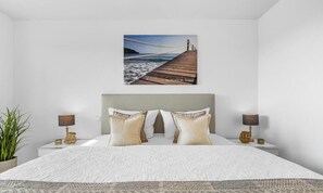A bedroom with a large bed, two bedside tables, a headboard, and a wall-mounted painting of a pier. - St. Tropez - 2nd Floor, Balcony, Harbor View, Private Parking, Washing Machine (Olpenitz)