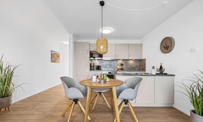 A modern kitchen with white cabinets, a round wooden table, and two grey chairs. - St. Tropez - 2nd Floor, Balcony, Harbor View, Private Parking, Washing Machine (Olpenitz)