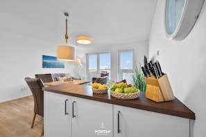 Eine moderne Küche mit Holzauszug, weißen Schränken und einer Pendelleuchte.