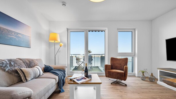 Ett modernt vardagsrum med en soffa, ett soffbord, en brun fåtölj och en tv.