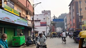 A busy street with various shops and buildings, including a visible sign for a car loan service. - Hotel Shree (Varanasi)