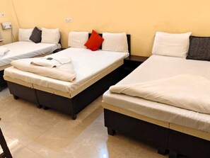 A hotel room with two beds, each with white bedding and pillows, and a small table between them.