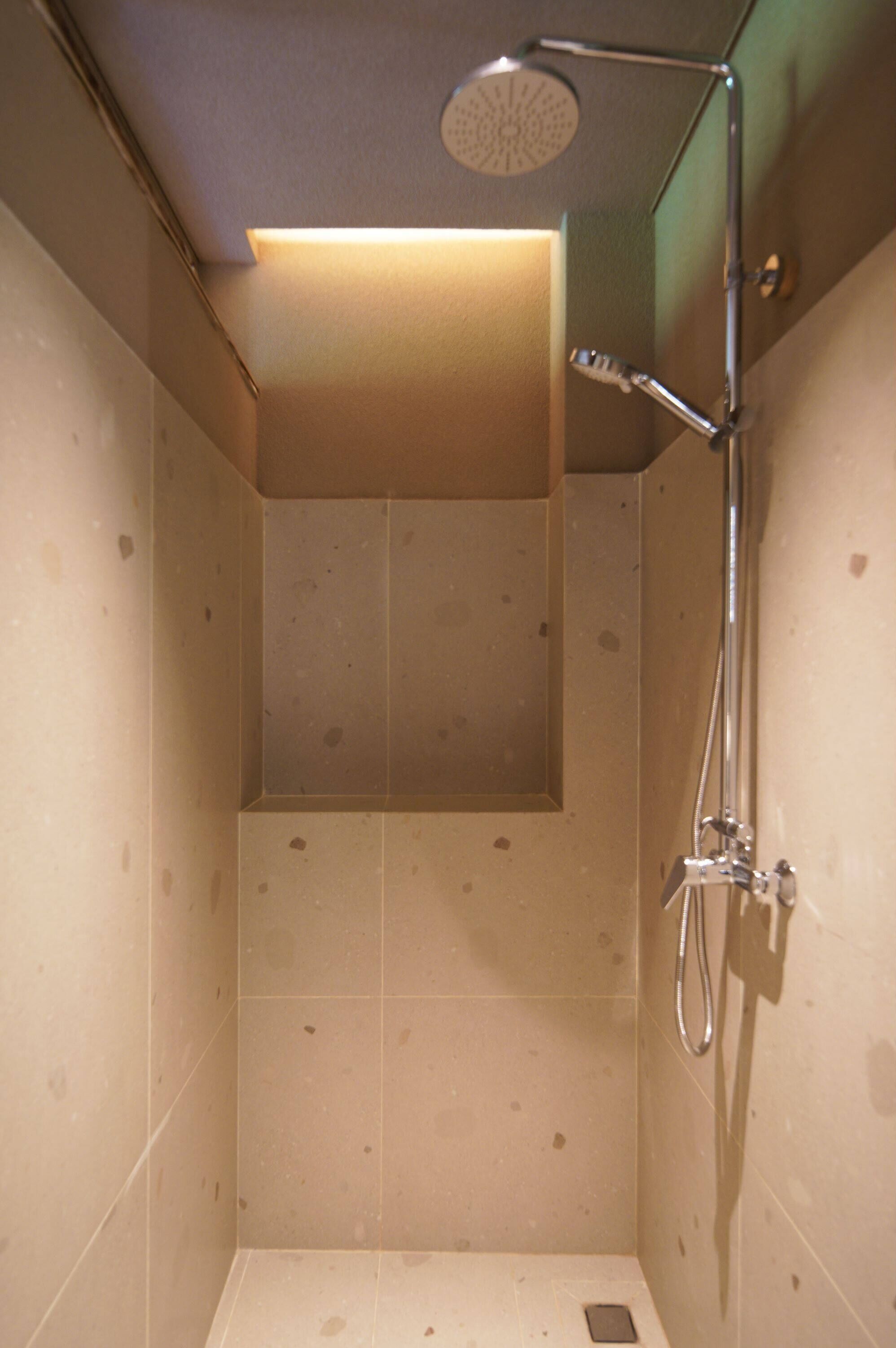 A small, enclosed shower area with a handheld showerhead and a wall-mounted faucet.
