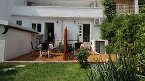 Un edificio a due piani con un patio arredato con mobili da esterno e un giardino.