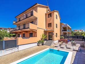 Ein mehrstöckiges Gebäude mit Swimmingpool, Außenbereich und blauem Himmel.