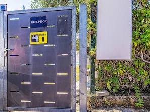 A metal reception desk with a 'Check-in' sign, a 'Reception' sign, and a blank sign on the right. - Suite(keine Küche) by Interhome (Krk/Milohnići)
