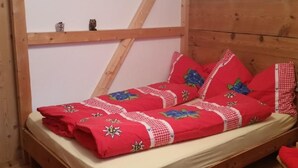 Una cama litera de madera con colcha y almohadas a cuadros rojos y blancos.