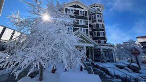 Ein mehrstöckiges Gebäude mit einem Uhrturm, schneebedeckten Bäumen und blauem Himmel.