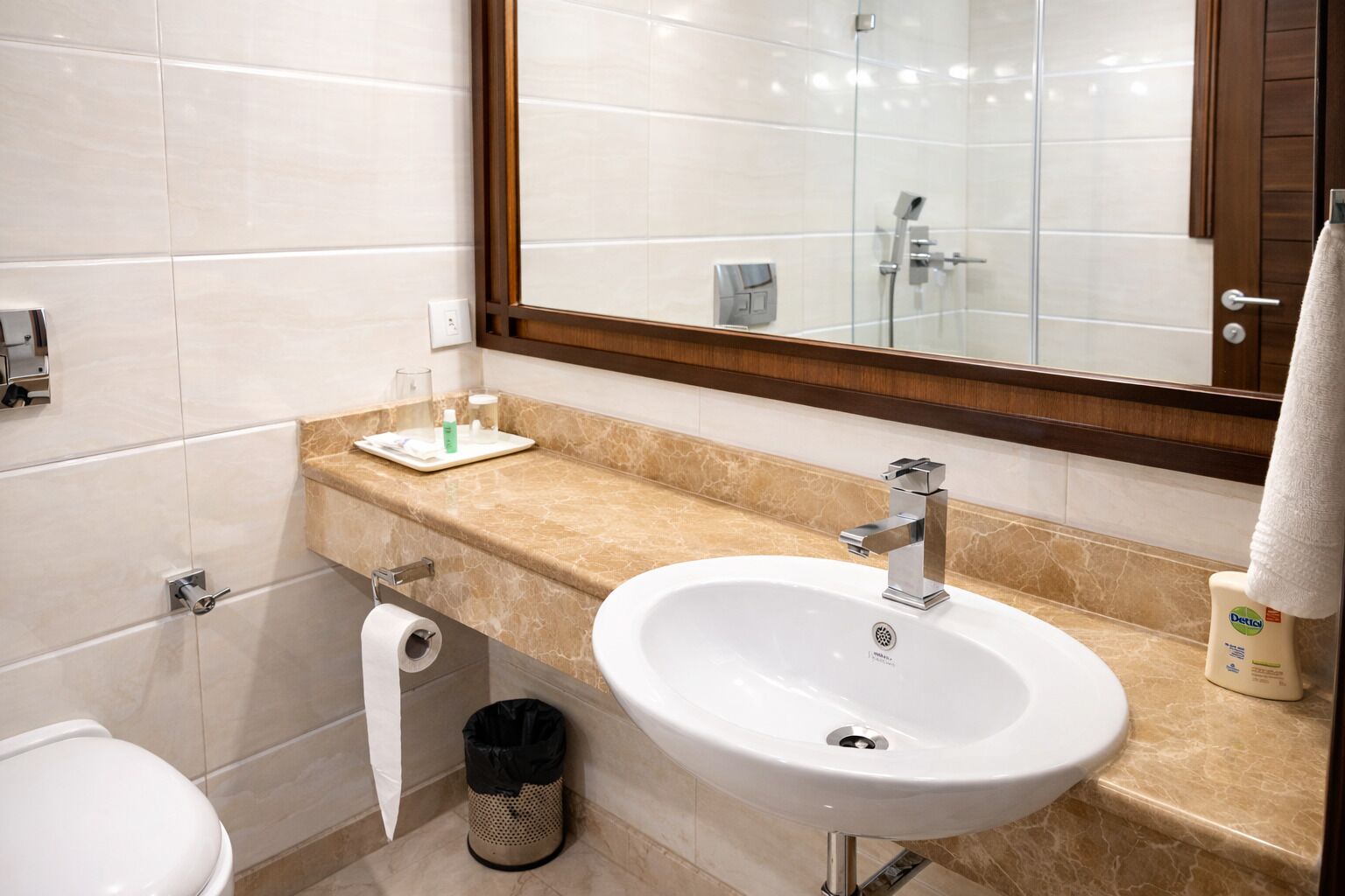 A bathroom with a white sink, a mirror, and a towel hanging on the wall.