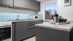 Eine moderne Küche mit grauen Schränken, einer Mikrowelle, einem Wasserkocher und einem Spülbecken.