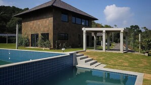 A modern house with a swimming pool, a covered patio, and a well-maintained lawn. - Sonemale Resort Chikmagalur (Mudigere)