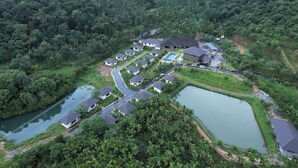 An aerial view of a residential area with houses, a swimming pool, and a small lake. - Sonemale Resort Chikmagalur (Mudigere)