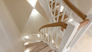 Una escalera con barandales blancos y pasamanos de madera que conduce a un piso superior.