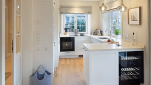 Una cocina moderna con una isla central, horno integrado y una bodega para vinos.