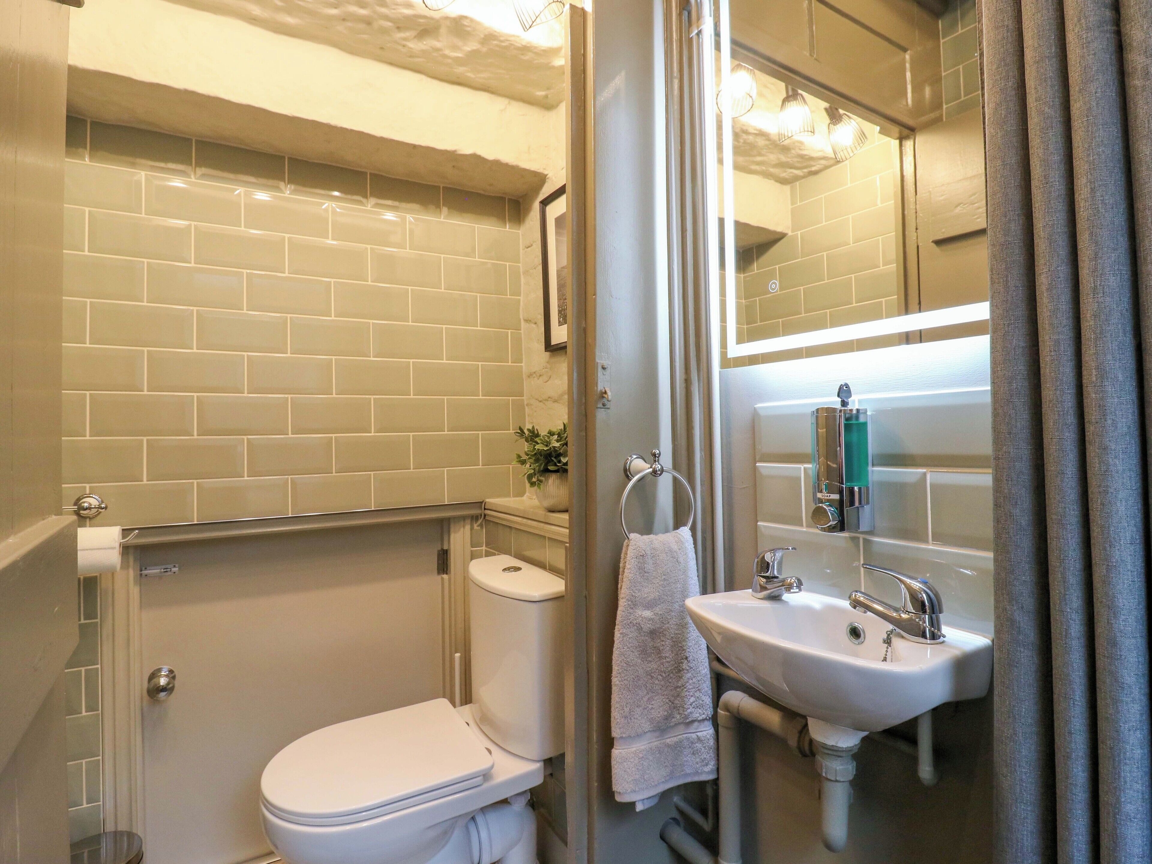A bathroom with a toilet, sink, and mirror.