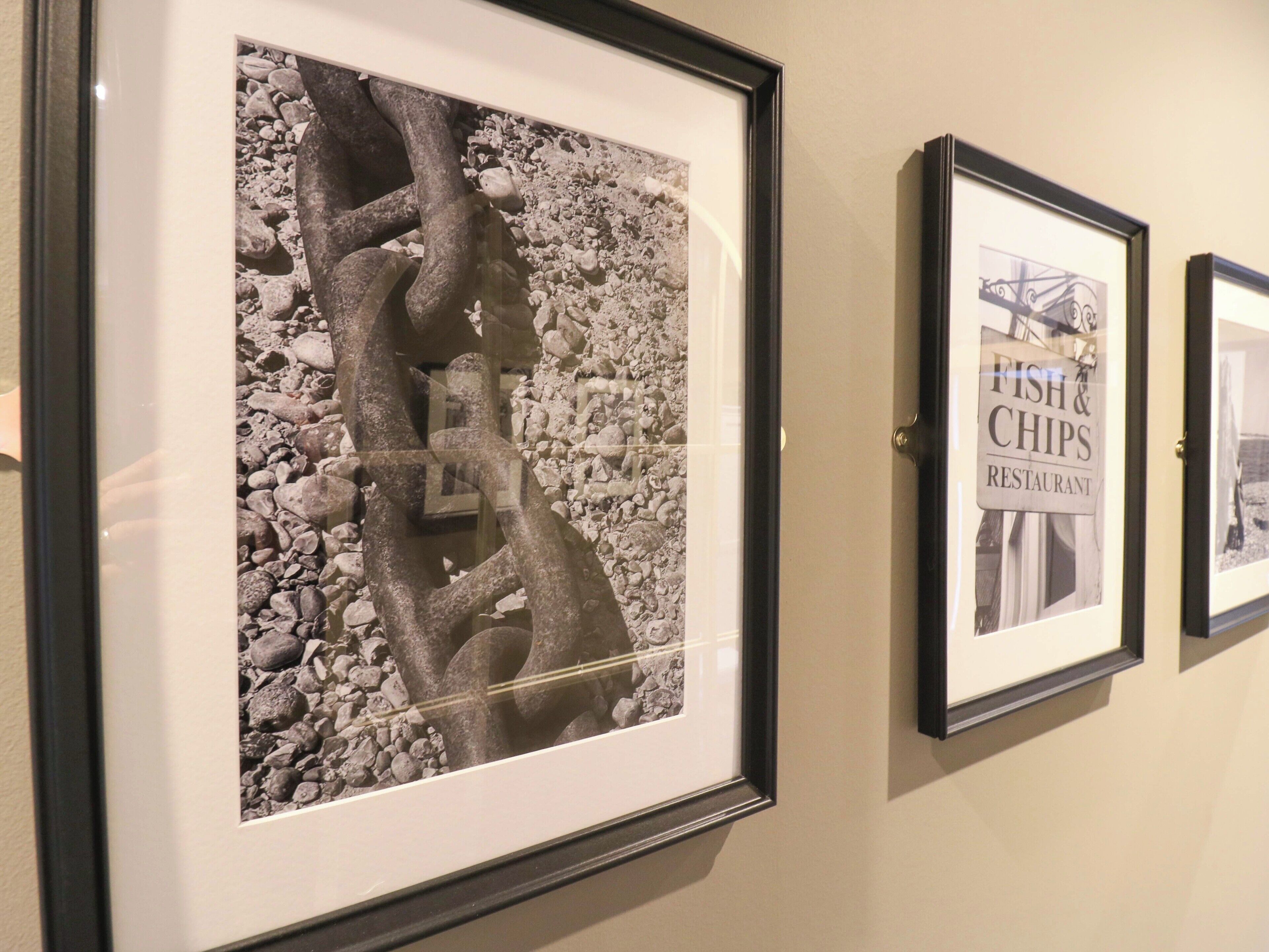 Framed artwork on a wall, including a piece with a rocky texture and another with text reading "FISH & CHIPS RESTAURANT".