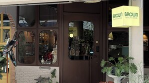 A storefront with a brown door, a sign reading 'BROWN MATCHA HOUSE,' and a bicycle parked outside. - Brown H (Bangkok)