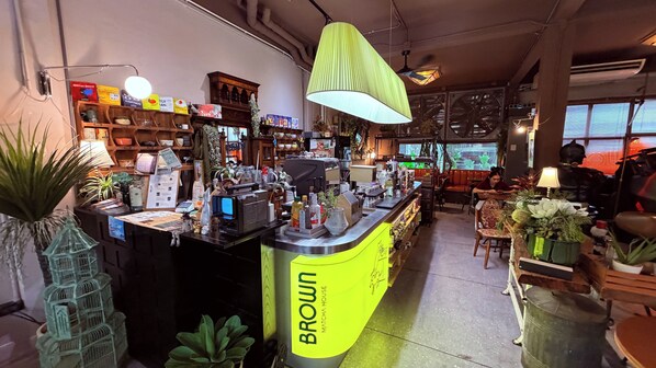 A coffee shop interior with a counter labeled 'Broun' and a seating area with tables and chairs. - Brown H (Bangkok)