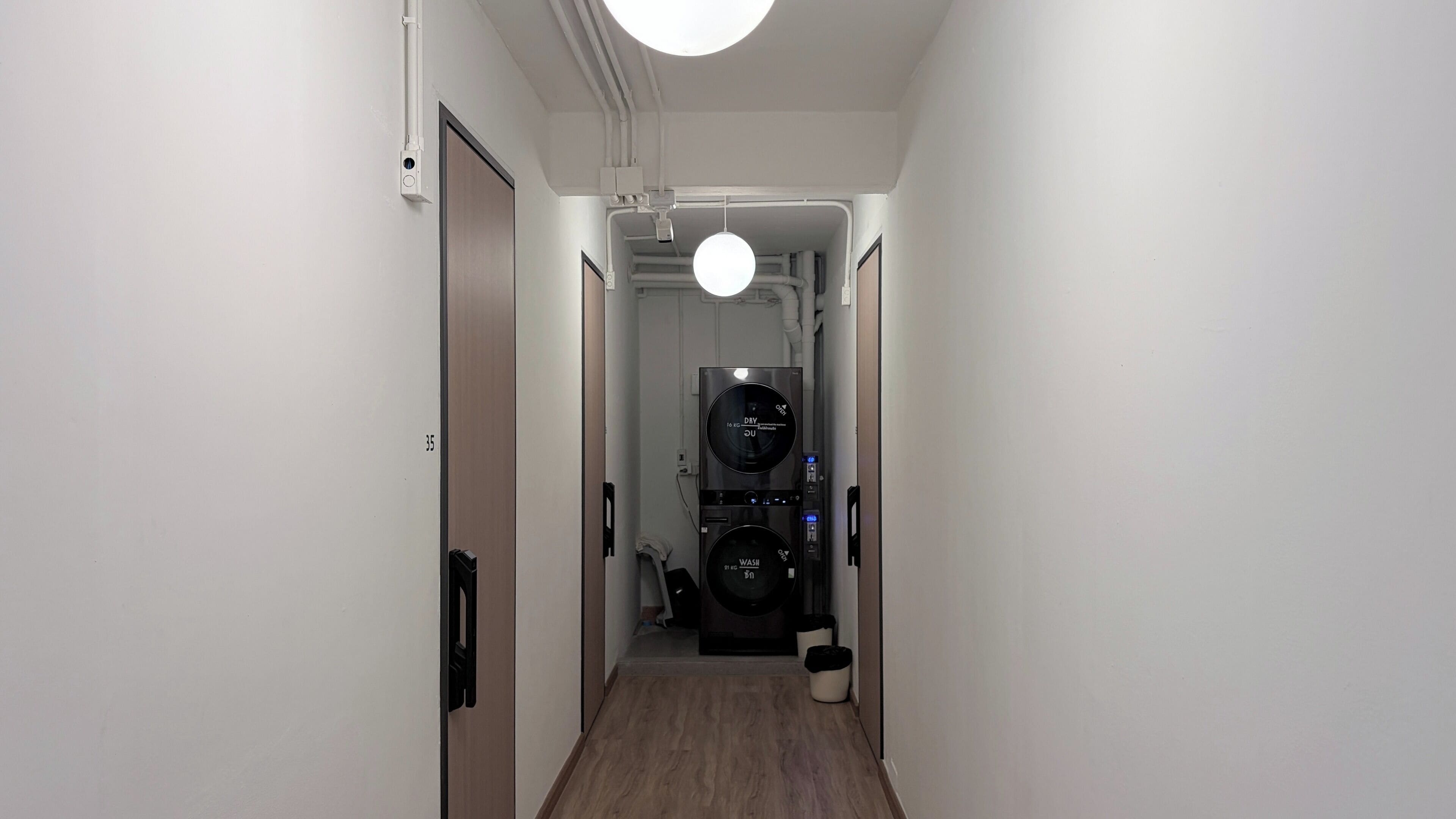 A narrow hallway leading to a laundry area with a washing machine and dryer.