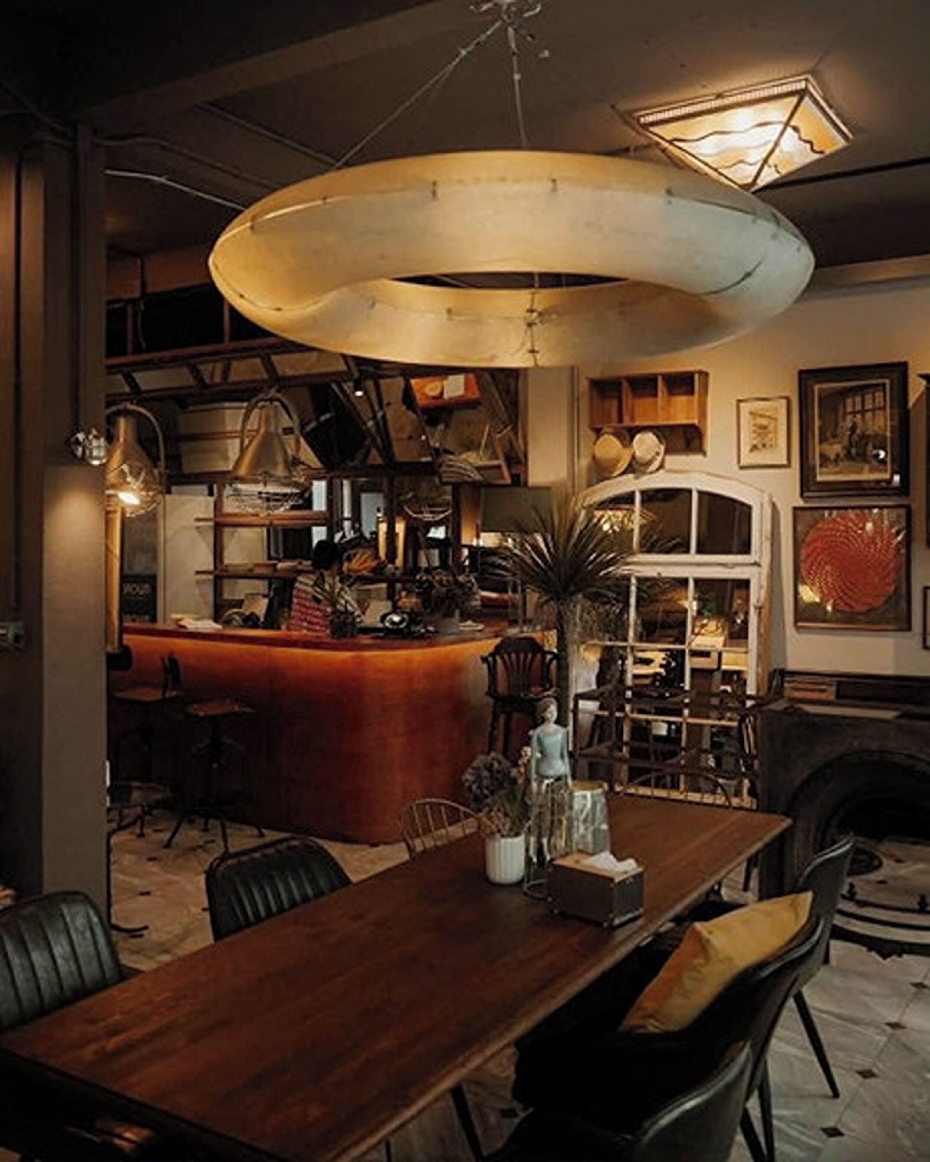 A dining area with a wooden table, chairs, a bar, and a large hanging light fixture.