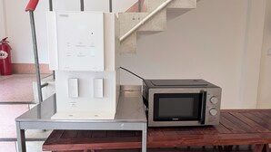 A kitchen area with a microwave and a water dispenser on a metal table. - Brown H (Bangkok)
