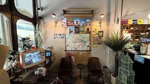 A cozy room with a large window, a map on the wall, and various items on shelves. - Brown H (Bangkok)