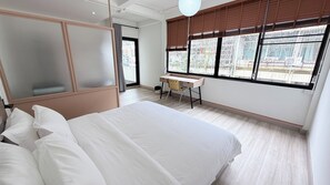 Une chambre d’hôtel avec un lit, un bureau et une fenêtre équipée de stores.