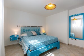 A bedroom with a bed, bedside tables, a mirror, and a hanging light fixture. - Villa 'Lory' with Mountain View, Private Pool and Wi-Fi (Castiadas)