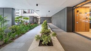 Un pasillo moderno con una puerta de madera, una maceta con plantas y un suelo de baldosas.