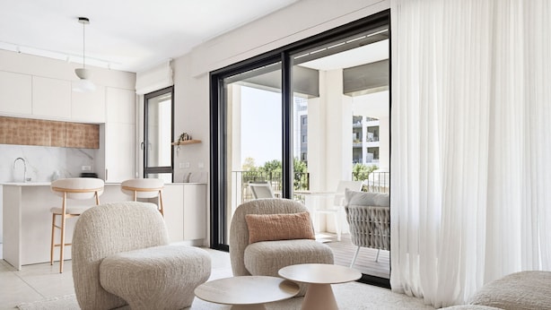 Una sala moderna con un sofá, dos mesas redondas y vistas a un balcón exterior.