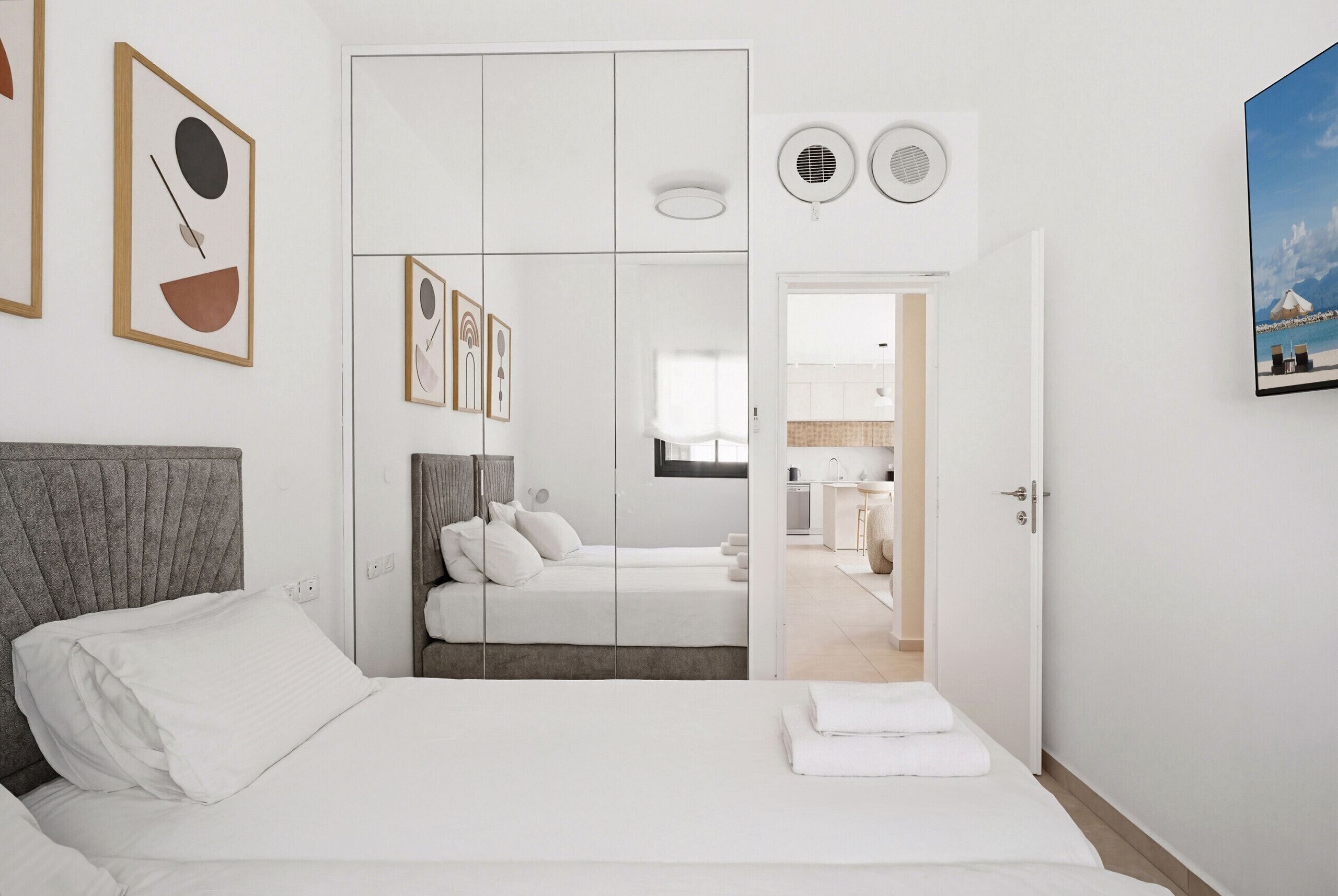 Ein modernes Hotelzimmer mit Bett, Kleiderschrank, Bad und Blick auf den Strand.