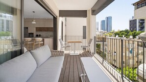 Un balcón con sofá, sillas, una mesa y vistas a la ciudad.