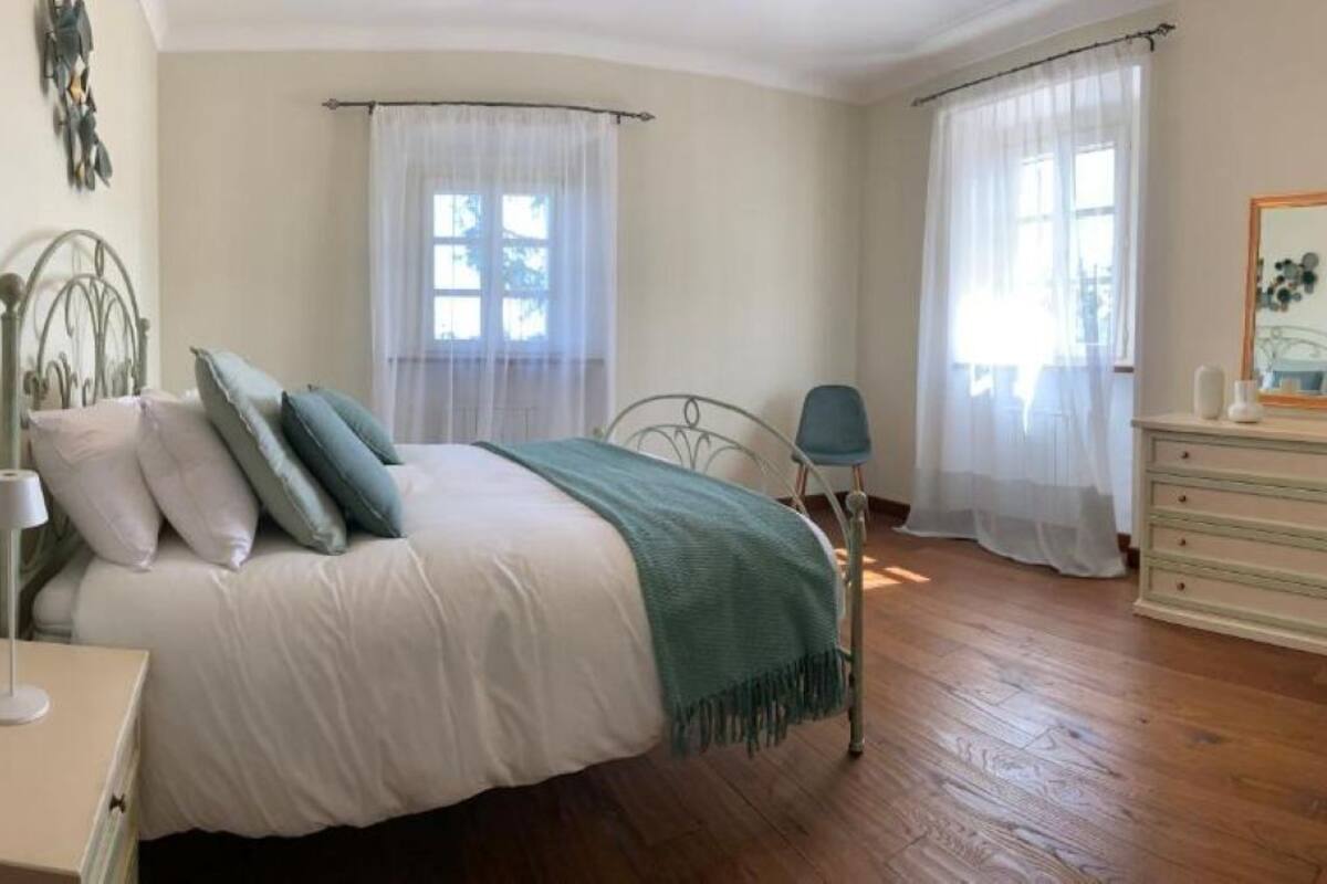 A bedroom with a bed, bedside table, chair, dresser, and a mirror.