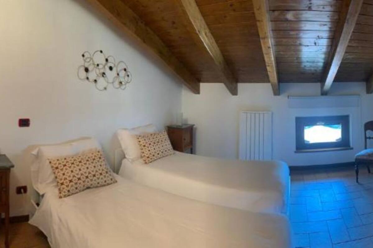 A bedroom with a bed, bedside tables, a window, and a wooden ceiling.