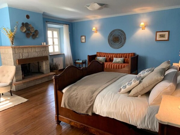 A bedroom with a large bed, a fireplace, a sofa, and a chair. - BORGO LA MORRA (Pavullo nel Frignano)