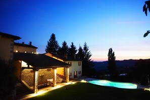 Une maison avec une piscine, une façade en pierre et un patio couvert.