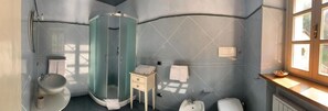 A bathroom with a glass shower enclosure, a sink, a toilet, and a vanity with a mirror. - BORGO LA MORRA (Pavullo nel Frignano)