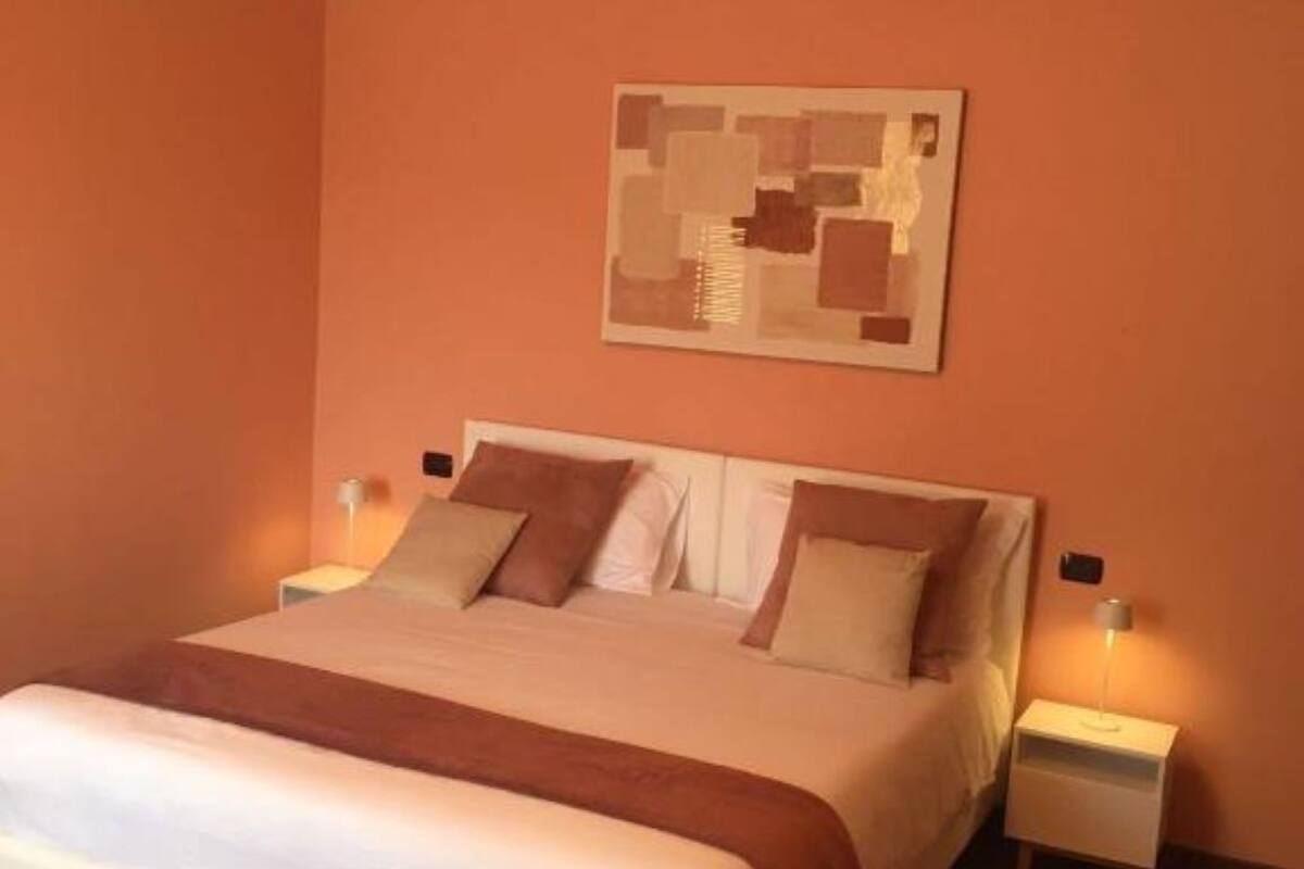 A bedroom with a bed, two bedside tables, and a wall-mounted artwork.