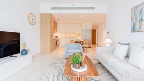 Una sala de estar moderna con televisor, sofá, mesa de centro y un comedor con mesa y sillas.