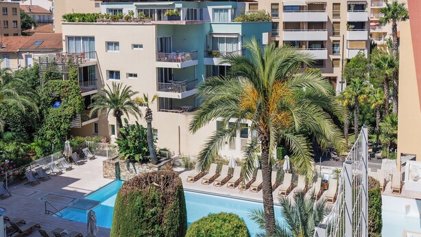 A rooftop pool area with sun loungers, palm trees, and a view of adjacent buildings. - Superb T2 with Port view Antibes Residence standing Clim Private Parking Wi-Fi (Antibes)