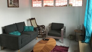 Ein Wohnzimmer mit einer Couch, zwei Sesseln, einem Holztisch und einem Bild an der Wand.