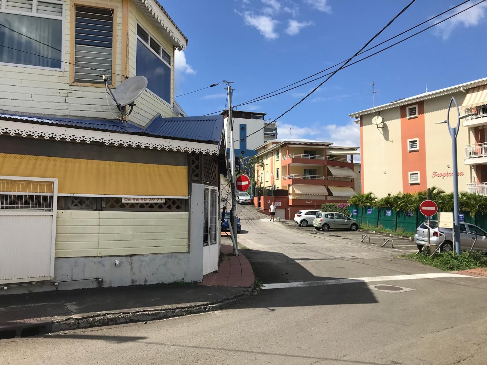 A street view with buildings, a no-entry sign, and parked cars.