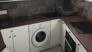Eine kleine Küche mit Waschmaschine, Mikrowelle und Spüle.