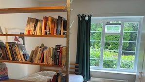 A room with a bunk bed, a red sofa, a bookshelf, and a window with curtains. - Artistic, 1930's studio-flat - 20 mins to Central London. (London)