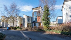 A modern residential building with a mix of glass and wood facade, a visible garage, and a paved driveway. - Family 3 Bedroom House by Guestz (Manchester)