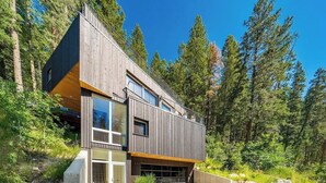 Eine moderne Holzhütte mit großen Fenstern, umgeben von einem Wald.
