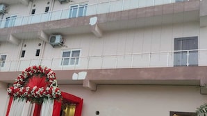 A multi-story building with balconies, air conditioning units, and a red and white floral decoration at the entrance. - Reeti Rivaaj Hotel Patna (Danapur)