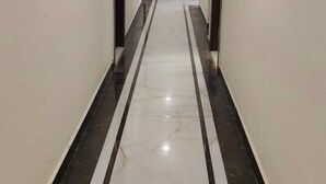 A hallway with white walls and a marble floor with black and white stripes. - Reeti Rivaaj Hotel Patna (Danapur)